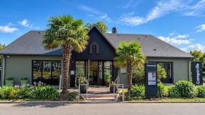 A building with a dark facade, a pitched roof, and a central entrance with glass doors.