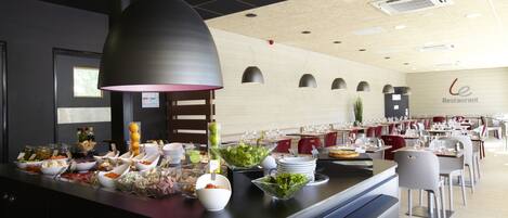 A buffet area with various food items and a seating area in the background.