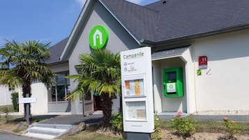 Welcome to Campanile, where a green logo marks the entrance to our modern hotel, featuring a wheelchair-accessible ramp and beautiful surroundings.