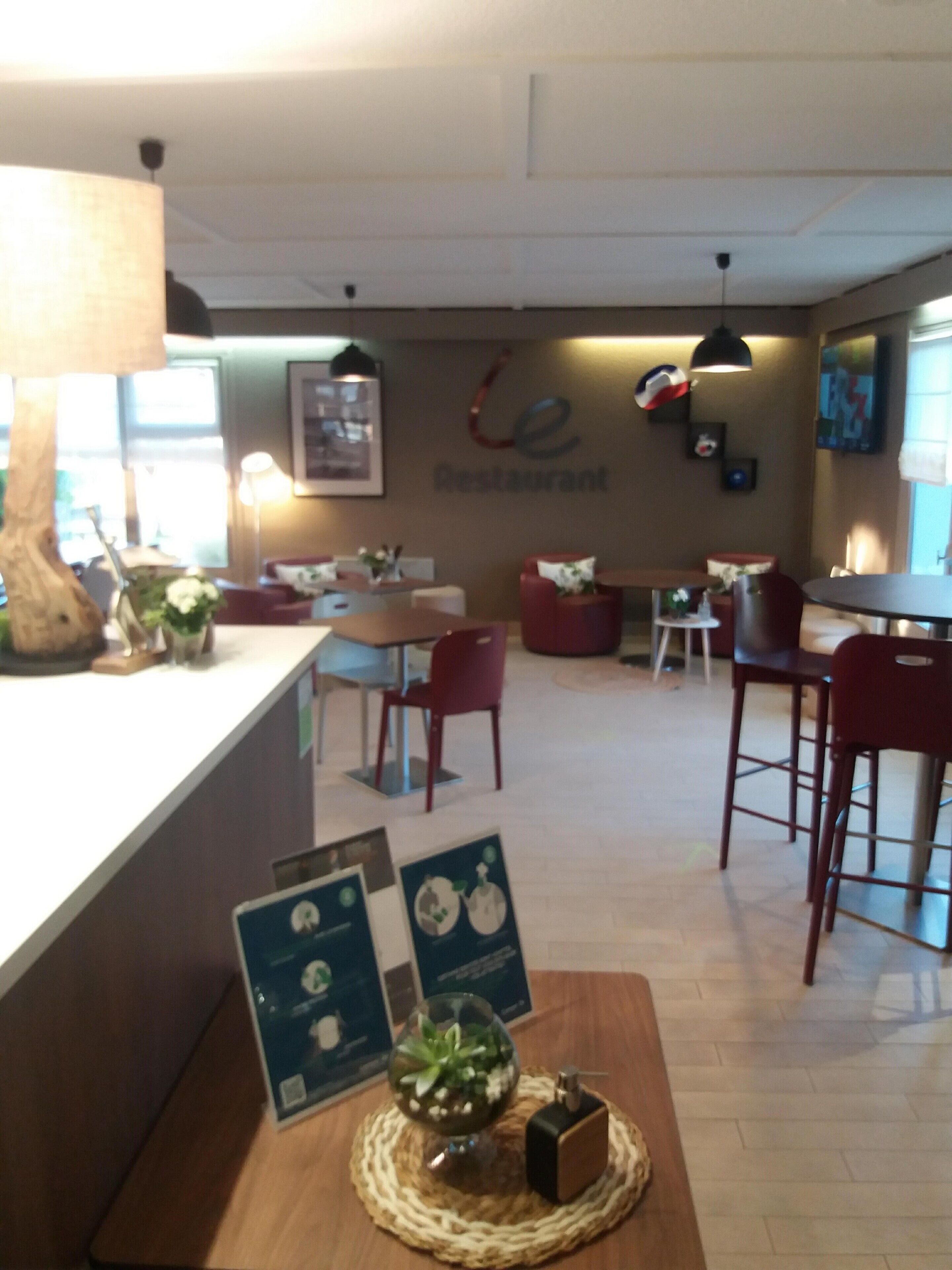 L'intérieur d'un restaurant, avec un comptoir, des tables, des chaises et un mur sur lequel est inscrit le nom du restaurant.
