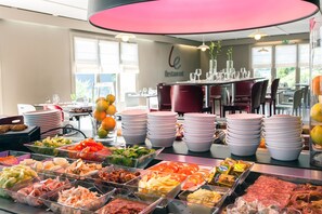 A buffet setup with various food items and stacked plates.