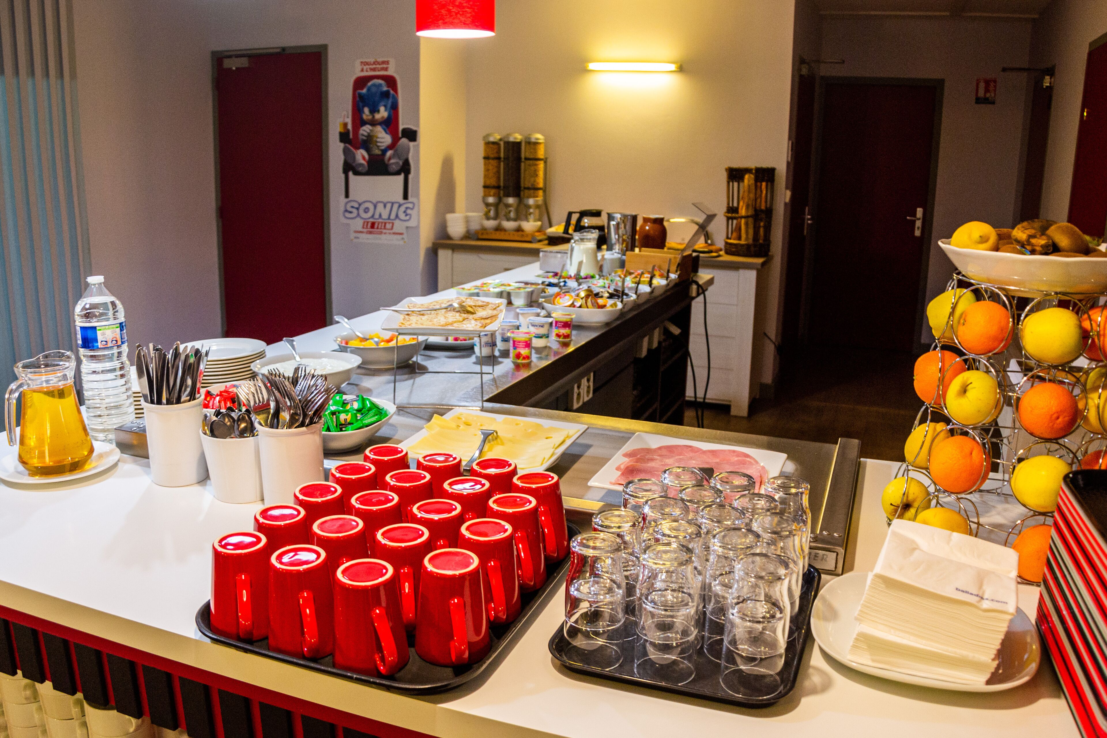 A buffet table with various food items, utensils, and a fruit display.