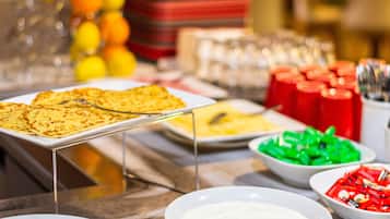 Una mesa de buffet con diversos alimentos, como panqueques, fruta y salsas.