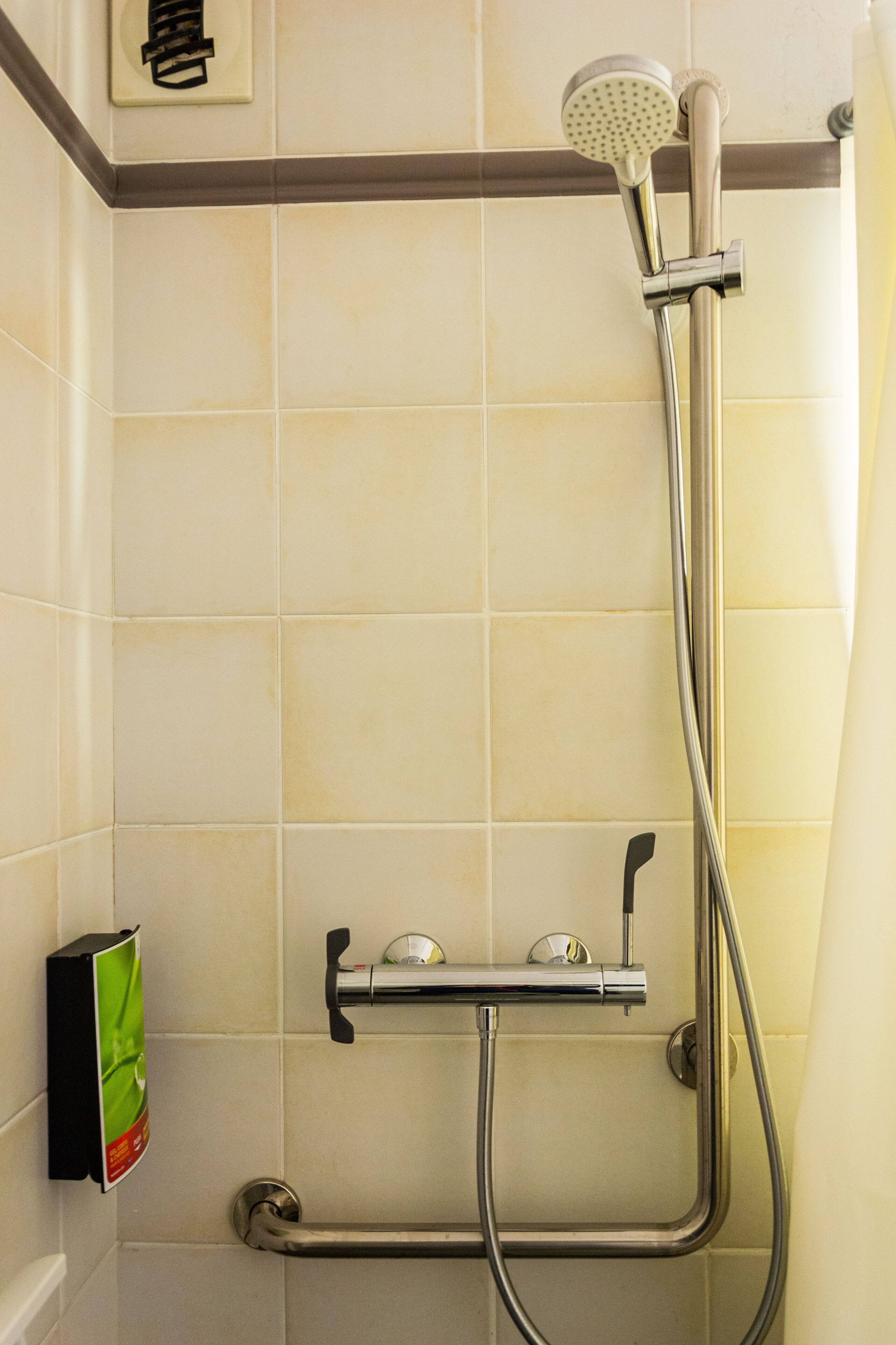 A shower with a handheld showerhead, a wall-mounted faucet, and a handheld shower hose.