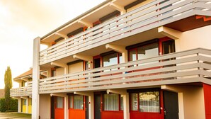 Un hotel de diverses plantes amb balcons, portes vermelles i un disseny arquitectònic modern.