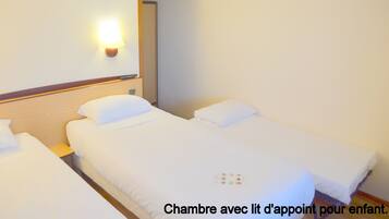 Quarto de hotel com duas camas, uma mesa de cabeceira e uma luminária fixada na parede.