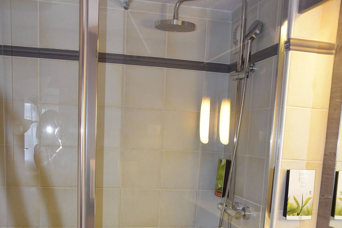 A modern bathroom with a glass-enclosed shower, a white sink, and a mirror above the sink.