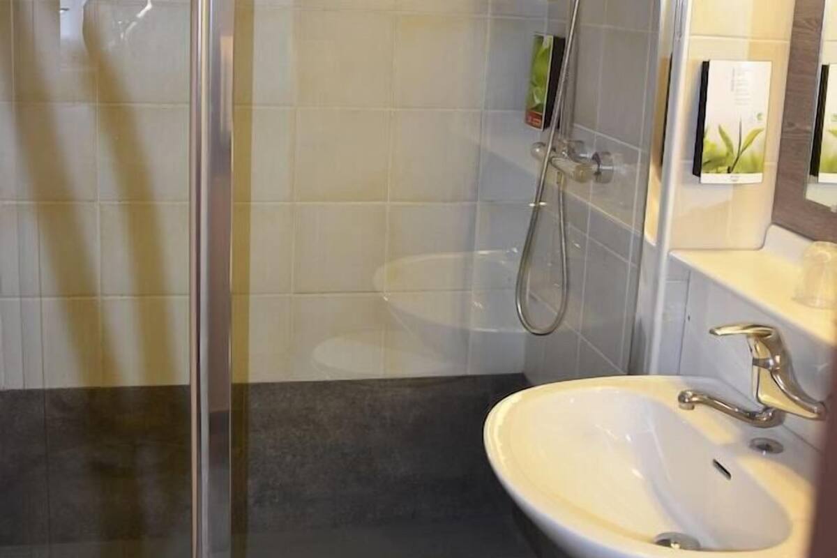 A modern bathroom with a glass-enclosed shower, a sink, and a mirror.