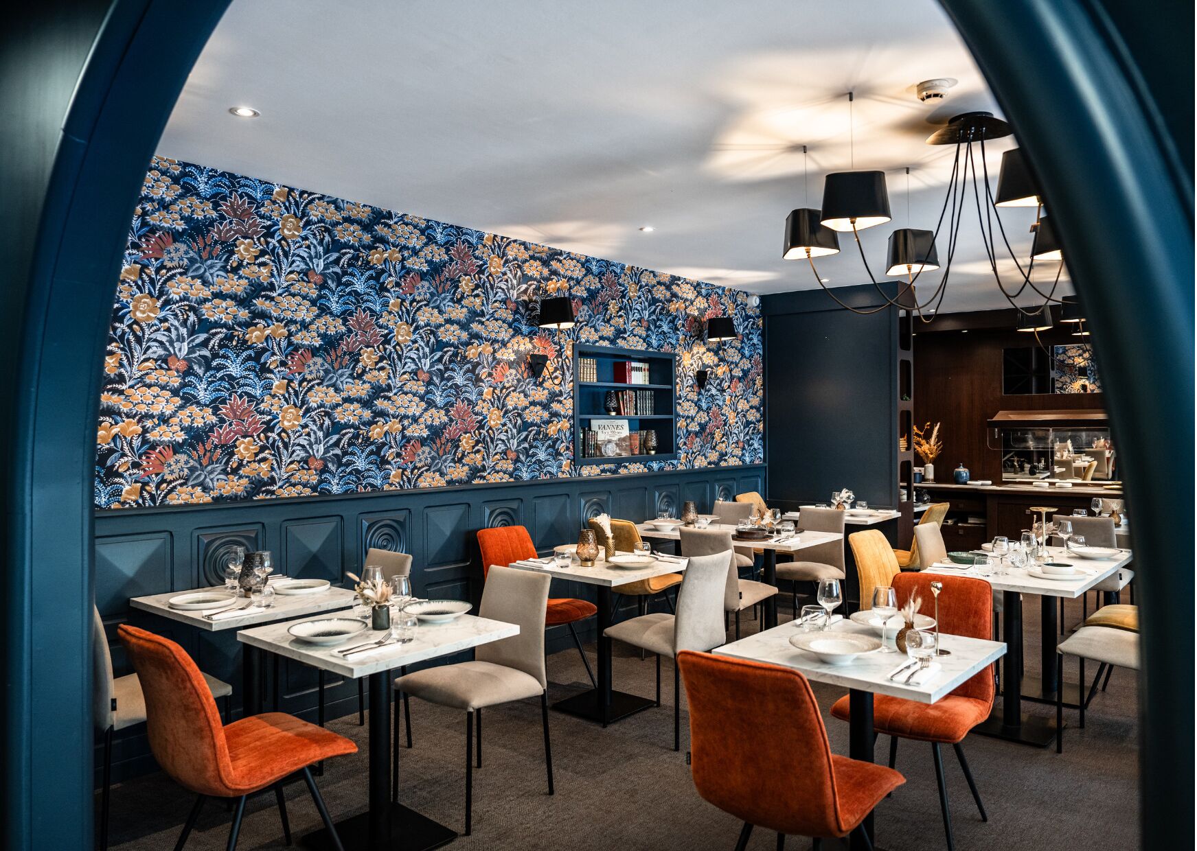 A restaurant with a patterned wall, multiple tables, and chairs.
