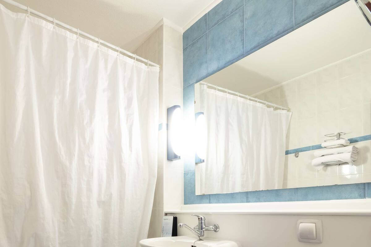 Un baño con bañera, lavabo, inodoro y espejo con iluminación.
