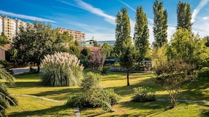 Un hôtel doté d’un jardin bien entretenu, de grands arbres et d’un ciel d’un bleu éclatant.
