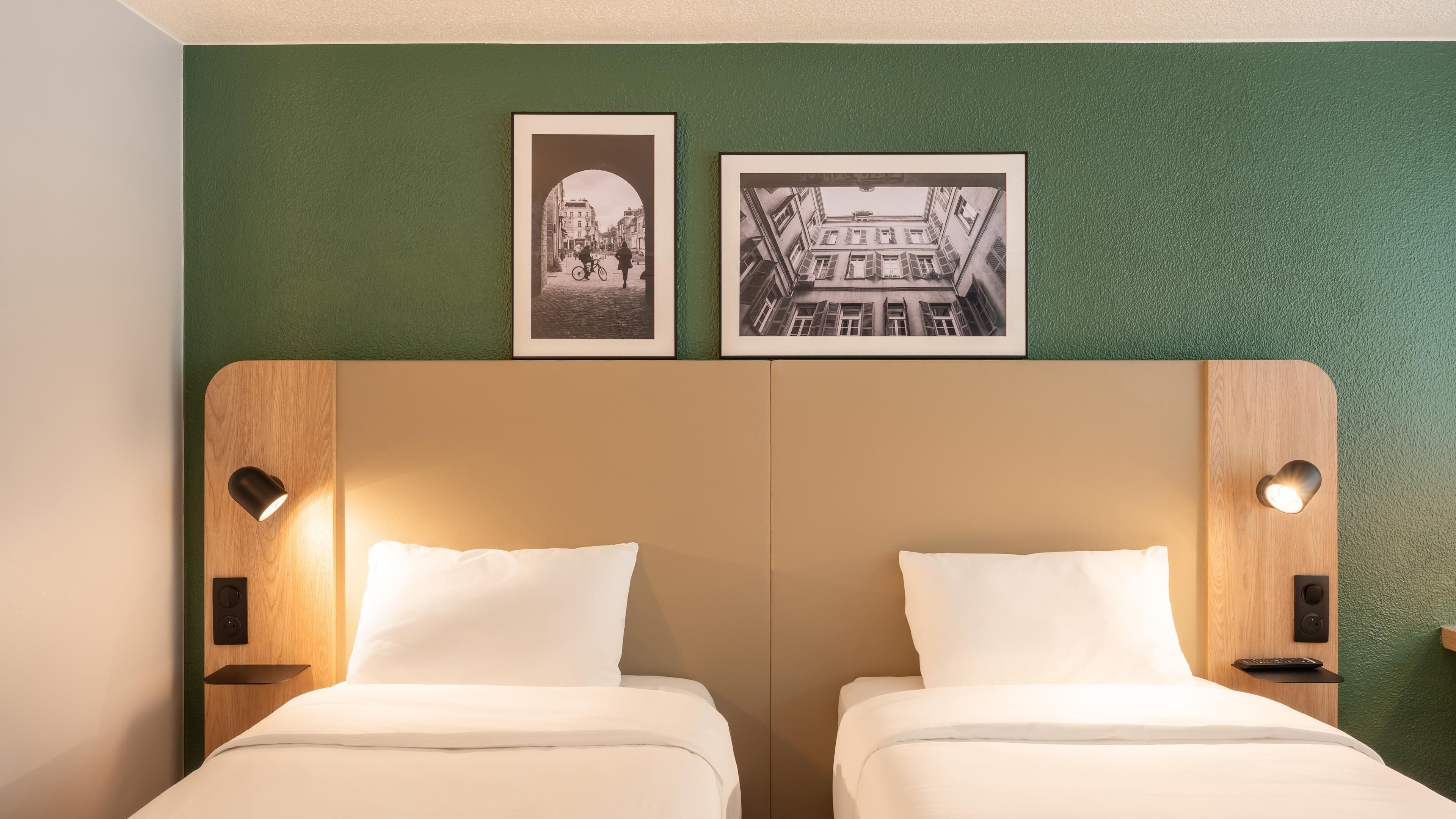 A double bed with a wooden headboard, two bedside tables with lamps, and two framed pictures on the wall.
