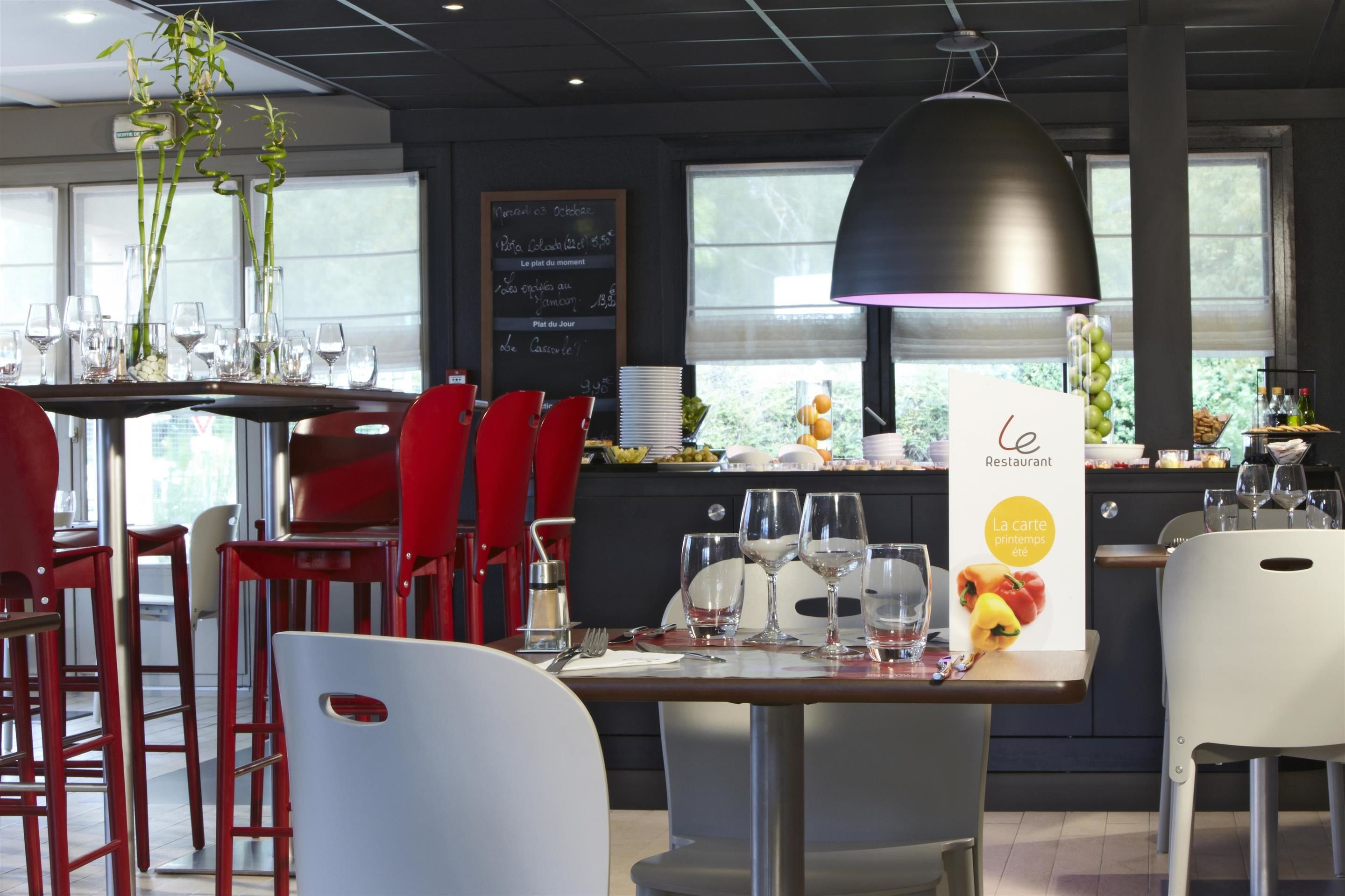Interior de un restaurante con sillas rojas, una lámpara colgante negra y un panel de menú.
