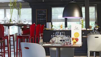 Interior de un restaurante con sillas rojas, una lámpara colgante negra y un panel de menú.