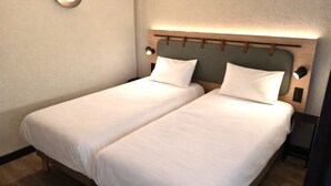 Cama doble con cabecera de madera y dos lámparas de noche.