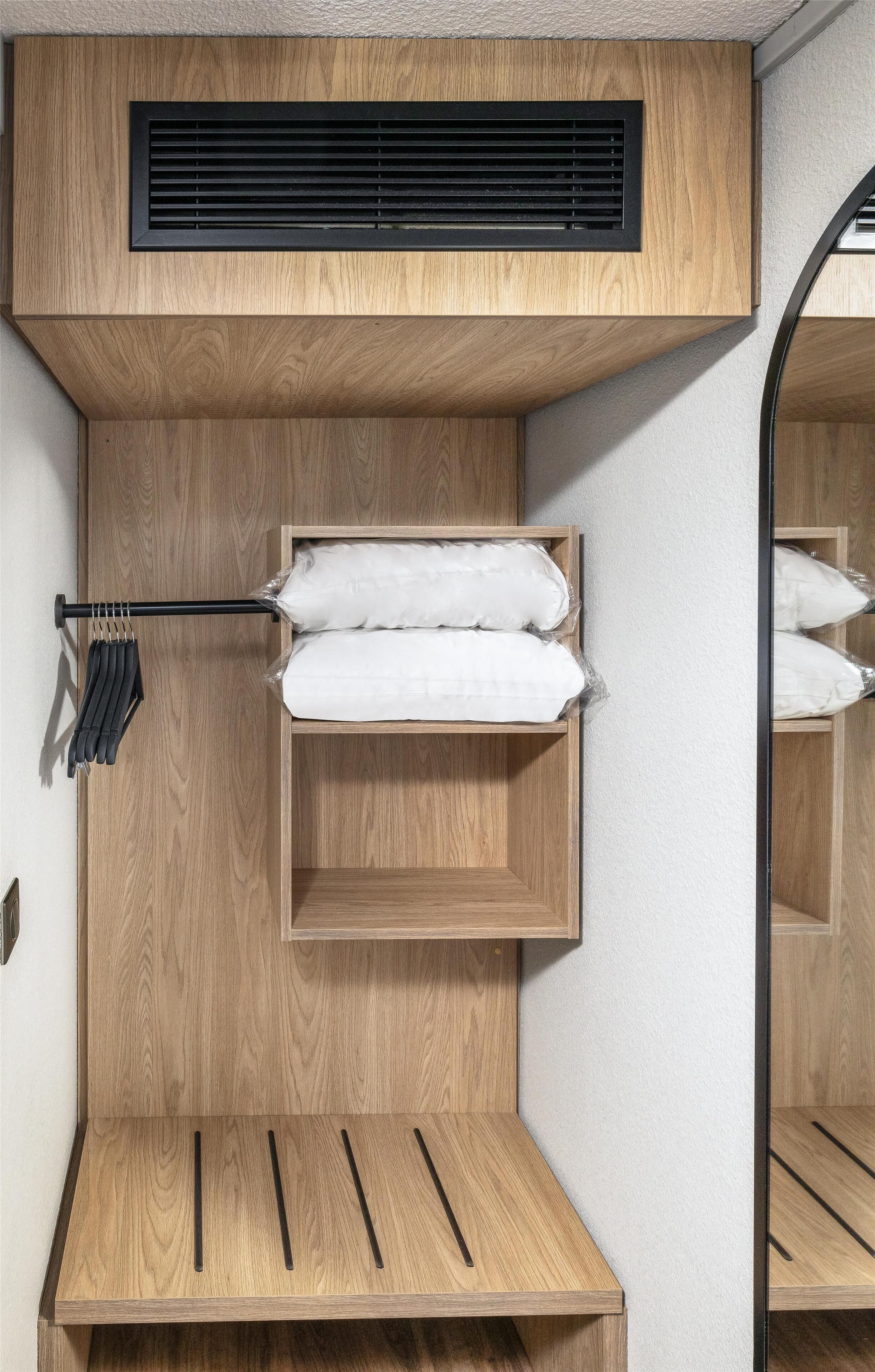 A compact, multi-level wooden storage unit with a built-in heater, a hanging rack, and a shelf.
