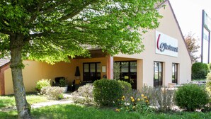 Un restaurante con letrero, mesas al aire libre y un jardín bien cuidado.