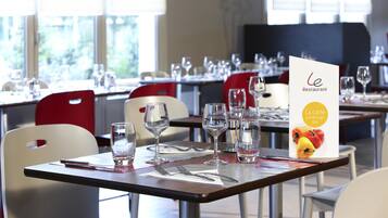 Un restaurante con mesas dispuestas para comer, incluyendo cubiertos y vasos.