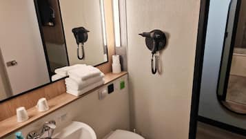 Un baño de hotel con lavamanos, inodoro, espejo, toallero y teléfono.