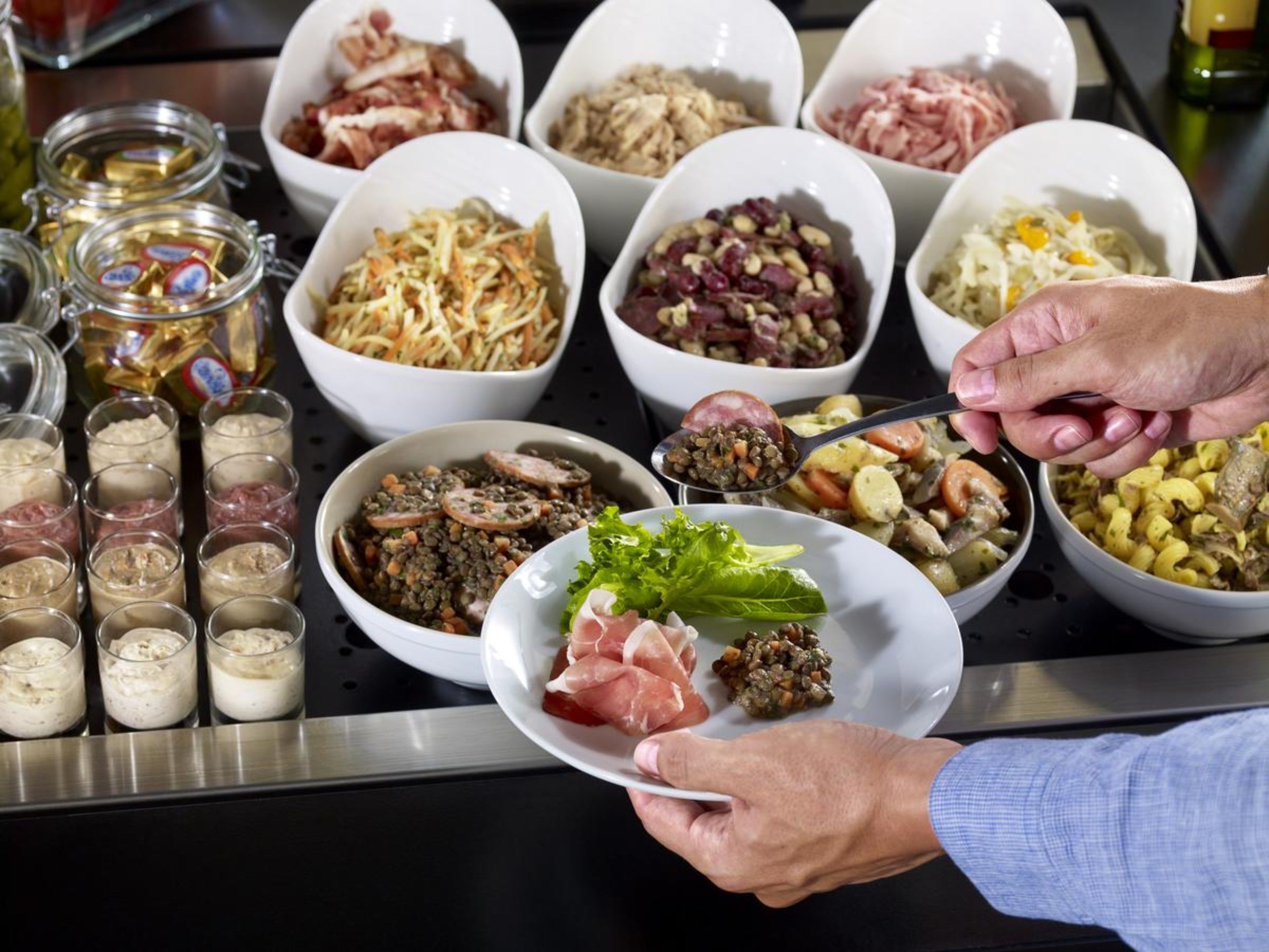 A buffet table with various dishes and condiments.
