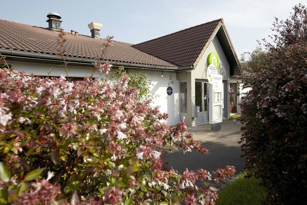 A building with a tiled roof, a sign indicating a restaurant, and a pathway leading to the entrance.