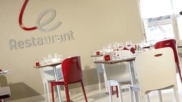 Interior de restaurante com mesas postas para refeições, cadeiras e um letreiro na parede.