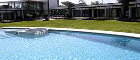 A modern building with a swimming pool in front.