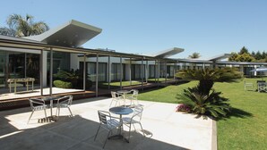 Eine moderne Außenpatio mit einem gläsernen Essbereich, Metallstühlen und einem kleinen Tisch.