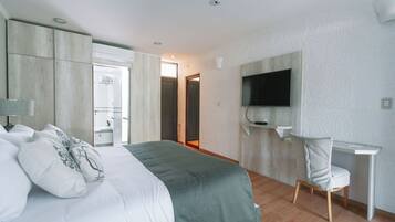 A modern hotel room with a large bed, a desk, and a TV mounted on the wall.