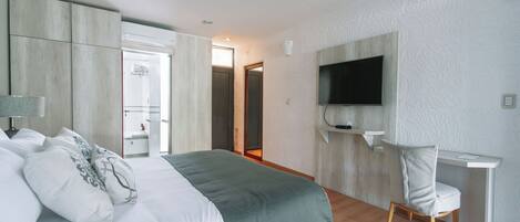 Una habitación de hotel moderna con una cama grande, un escritorio y un televisor fijado a la pared.