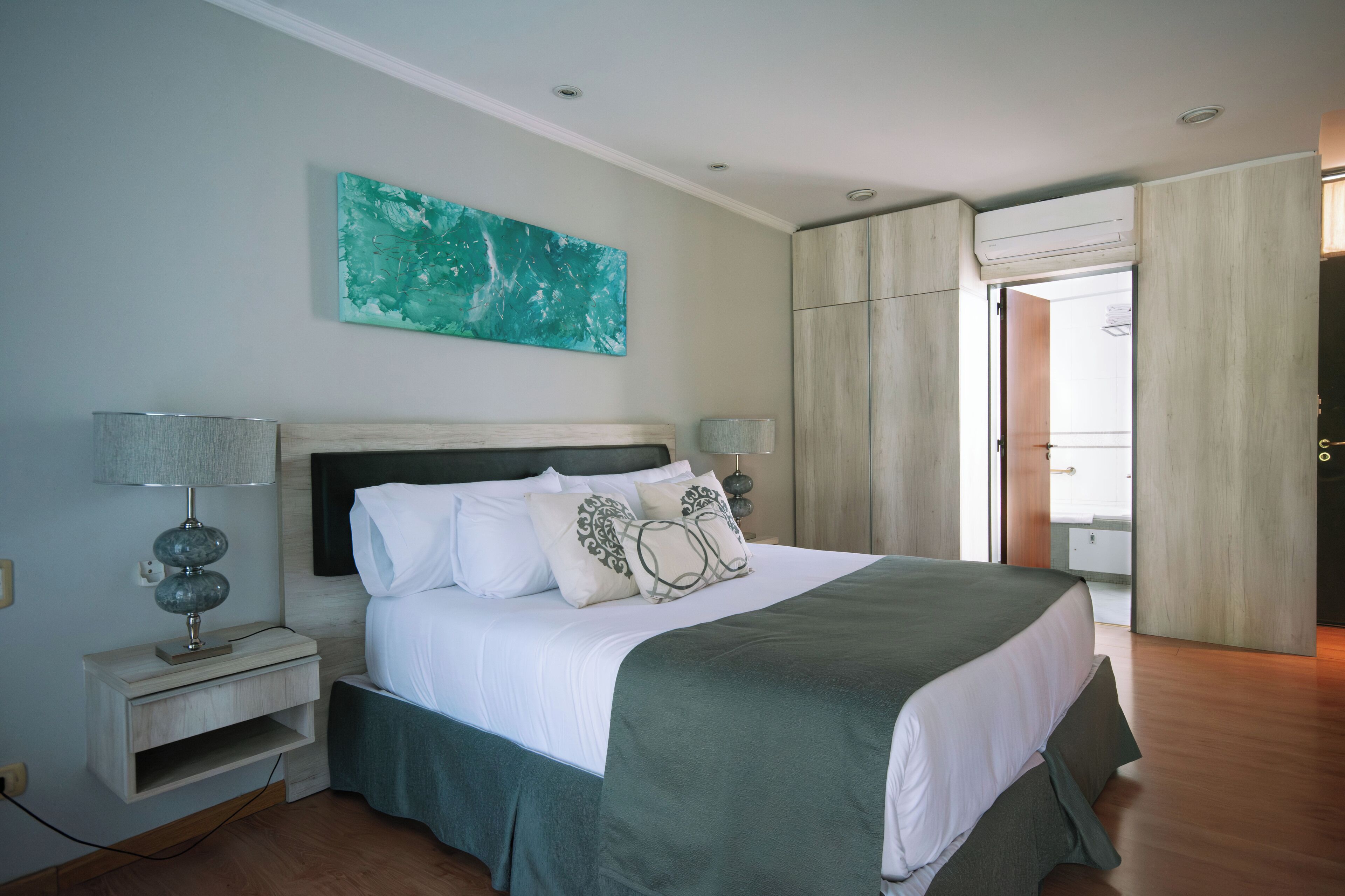 A bedroom with a bed, nightstands, a painting, and a wardrobe.