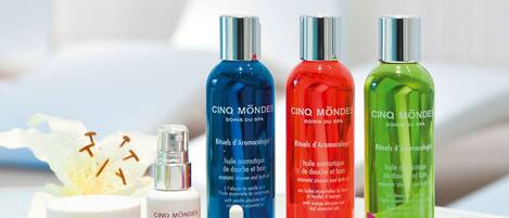A selection of Cinq Mondes spa products including oils and a jar of cream, arranged on a white surface with flowers.