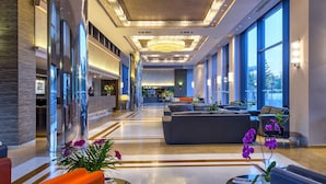 A spacious lobby with a reception desk, seating area, and large windows. - Porto Platanias Beach Resort & Spa (Platanias)