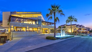 Een modern hotel met een glazen gevel, terras en een waterpartij.