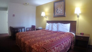 Una habitación de hotel con una cama grande, dos lámparas de noche, un escritorio y una silla.