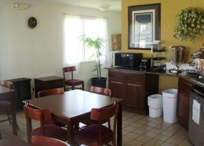 A compact kitchen with a dining area, a microwave, a sink, and a potted plant.