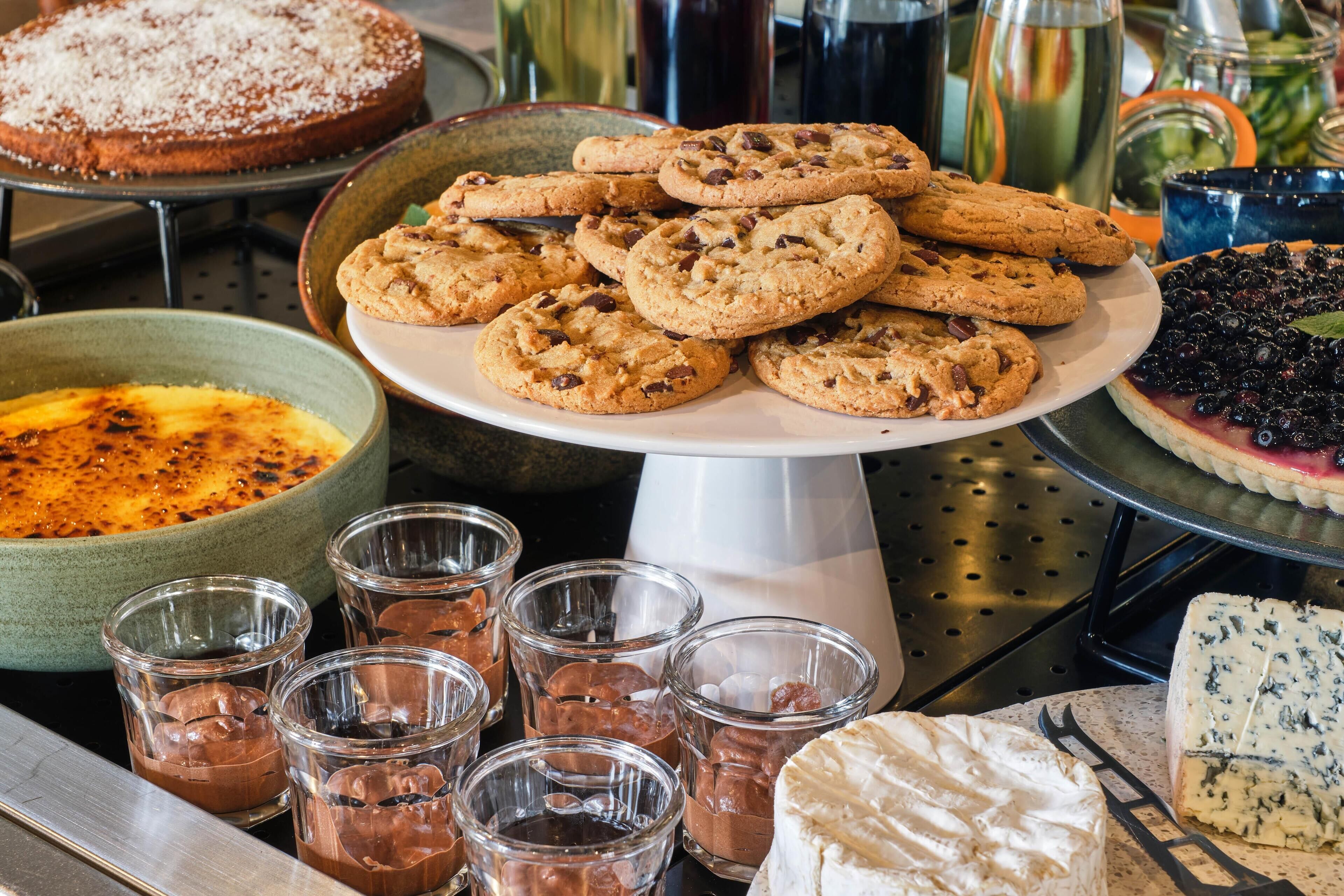 A dessert table with cookies, a pie, and glasses of chocolate mousse.