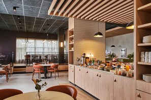 Un intérieur de restaurant moderne avec un bar pour le petit-déjeuner, des meubles en bois et un espace détente avec des tables et des chaises.