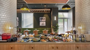 Un buffet proposant une variété de plats et d’ustensiles, des poutres en bois au plafond et des luminaires suspendus.