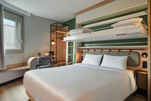 Een hotelkamer met een stapelbed, een bureau met stoel, een spiegel en een raam.