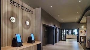 Un kiosque d’enregistrement automatisé doté d’un mur en panneaux de bois et d’un aménagement intérieur moderne.
