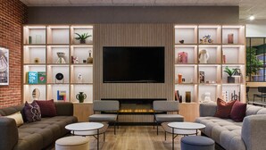 Un salon moderne doté d’un grand téléviseur à écran plat, de sièges confortables et d’une bibliothèque où sont exposés divers objets décoratifs.
