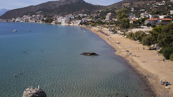 Un pueblo costero con playa despejada, afloramientos rocosos y edificios al fondo.