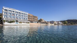 A waterfront hotel with multiple balconies, clear blue water, and a hilly backdrop. - Hotel Tolo (Nafplio)