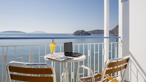 A balcony with a table, two chairs, a laptop, and a drink. - Hotel Tolo (Nafplio)