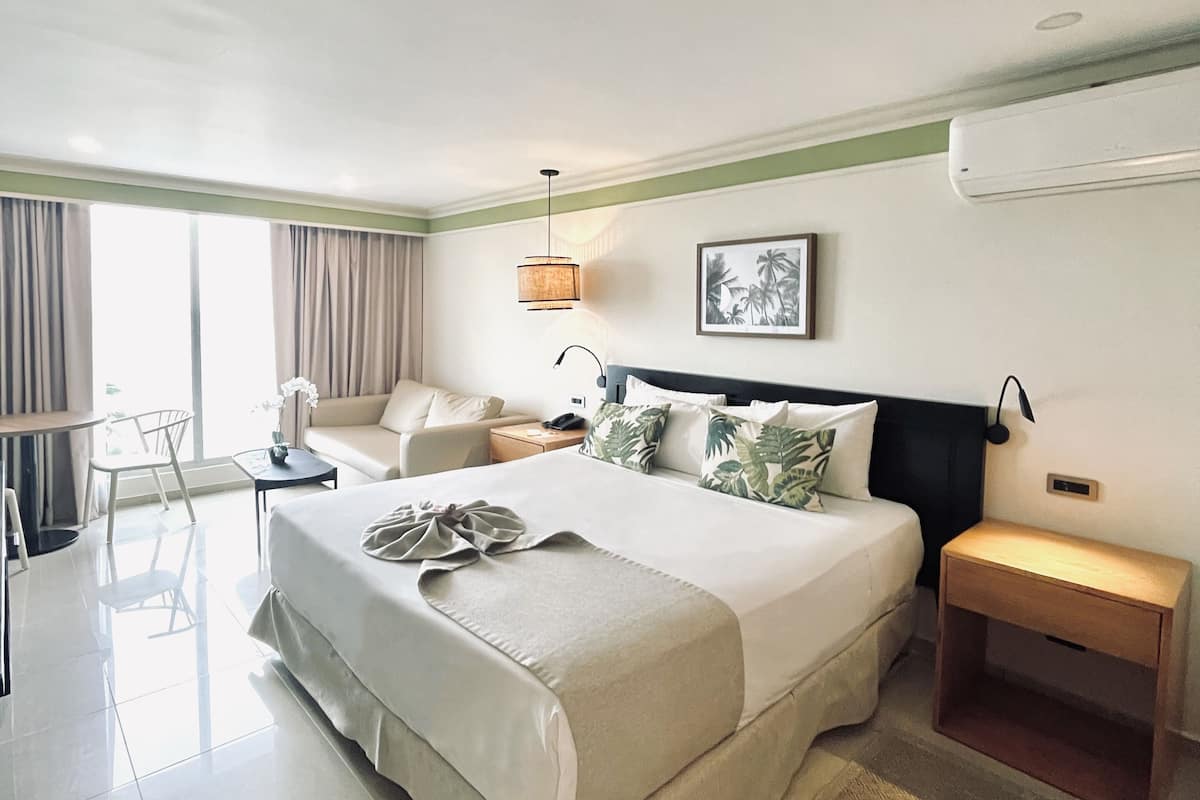 Une chambre d’hôtel avec un grand lit, un bureau, une chaise et une vue sur l’extérieur.