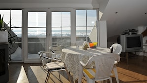 A dining area with a table and chairs, a television, and a view through large glass doors. - Geinberg Suites & Vianova Lodges (Polling im Innkreis)