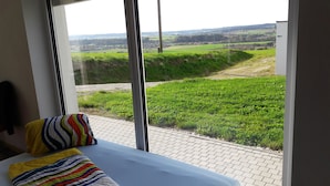 A bedroom with a large window overlooking a grassy landscape. - Geinberg Suites & Vianova Lodges (Polling im Innkreis)