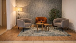 Una habitación moderna con dos sillones grises, una mesita de madera y una lámpara de pie.