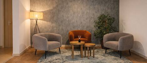 A modern room with two grey armchairs, a small wooden table, and a floor lamp.